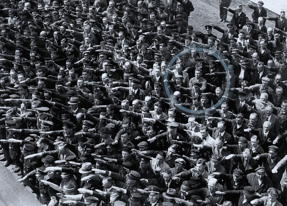 A man in a crowd stands defiantly with his arms crossed while his peers salute. Change takes courage.
